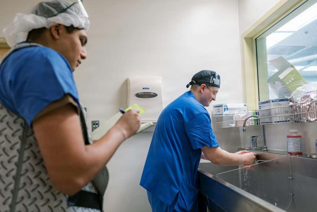 Two medical professionals washing hands at sink.