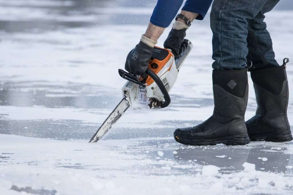 a man holding a chainsaw on top of ice